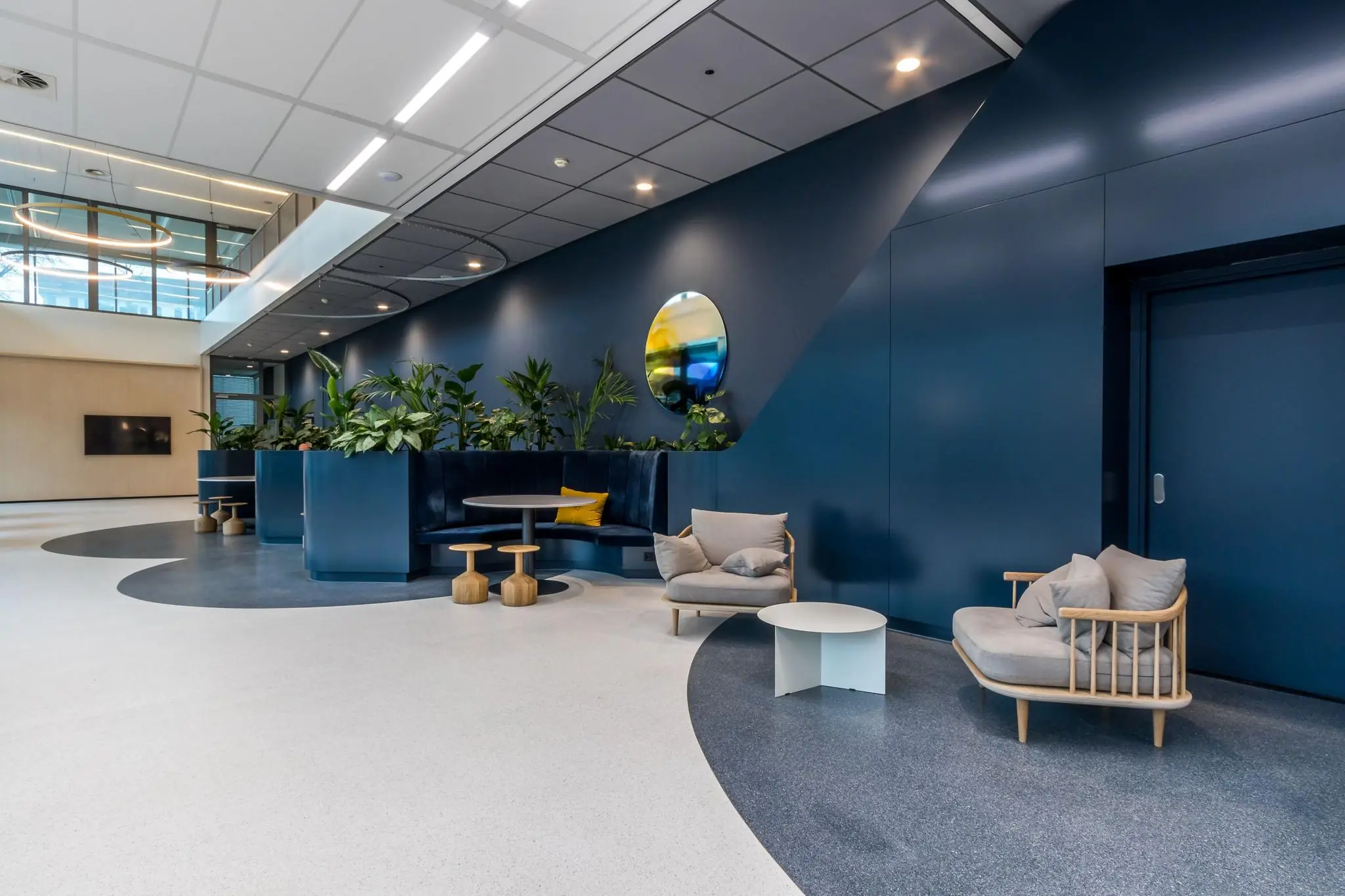 Moderne en open loungehoek aan de Vliegend Hertlaan met blauwe wanden, planten en zitplaatsen.